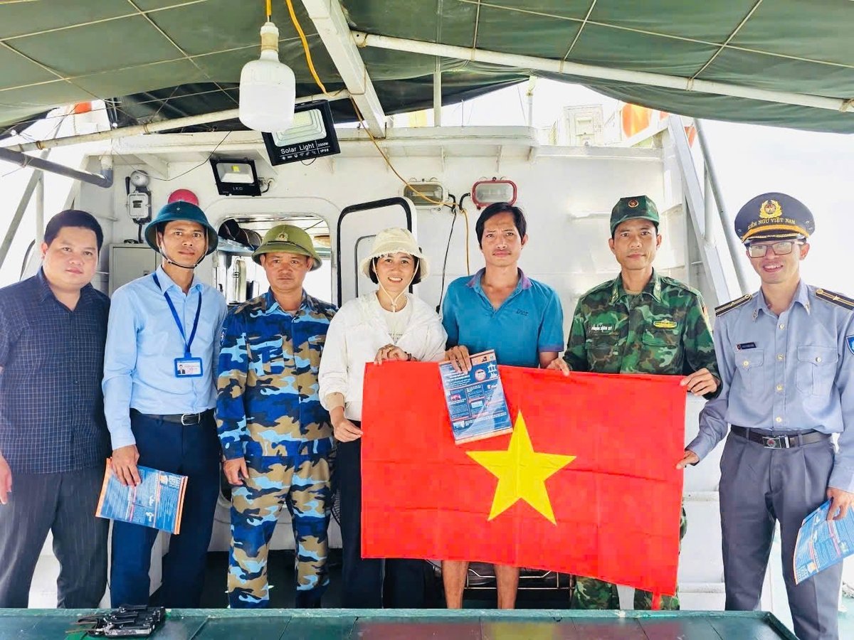 Phát tờ rơi tuyên truyền và trao tặng cờ Tổ quốc các chủ tàu hoạt động khai thác thủy sản trên biển. Ảnh: Hữu Tình.