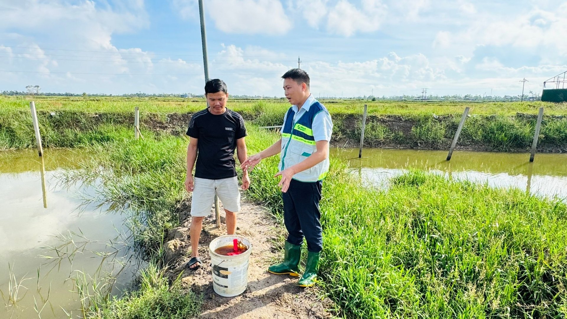 Ông Đặng Xuân Trường (phải) - Trưởng phòng Khuyến ngư (Trung tâm Khuyến nông Quốc gia) hướng dẫn hộ nuôi thủy sản quy trình xử lý ao nuôi bằng chế phẩm sinh học. Ảnh: Ánh Nguyệt.