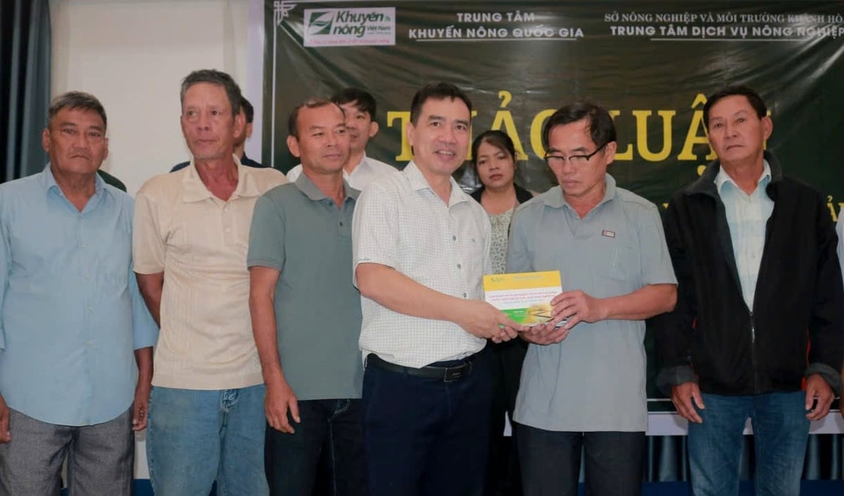 Đại diện Trung tâm Khuyến nông Quốc gia tặng cuốn sách về giải pháp kỹ thuật giúp bà con khôi phục sản xuất sau mưa lũ. Ảnh: KS.